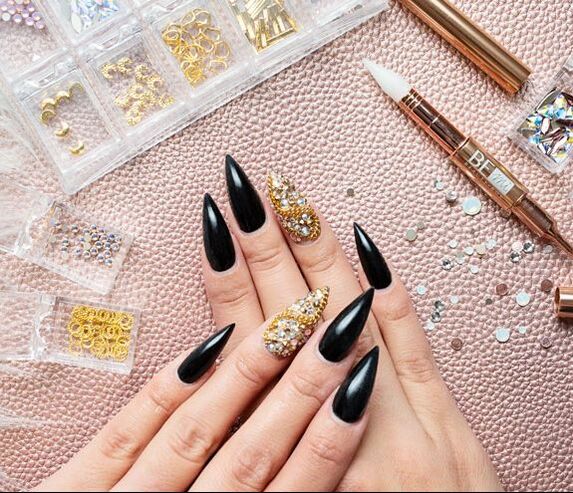 Set of gel nails with black stiletto nails and accent nail with swarovski crystals and gold accents 